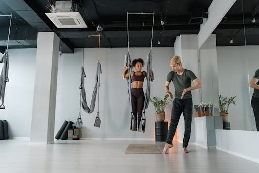 Aerial yoga session led by a professional instructor in a contemporary yoga studio, focusing on flexibility and fitness.