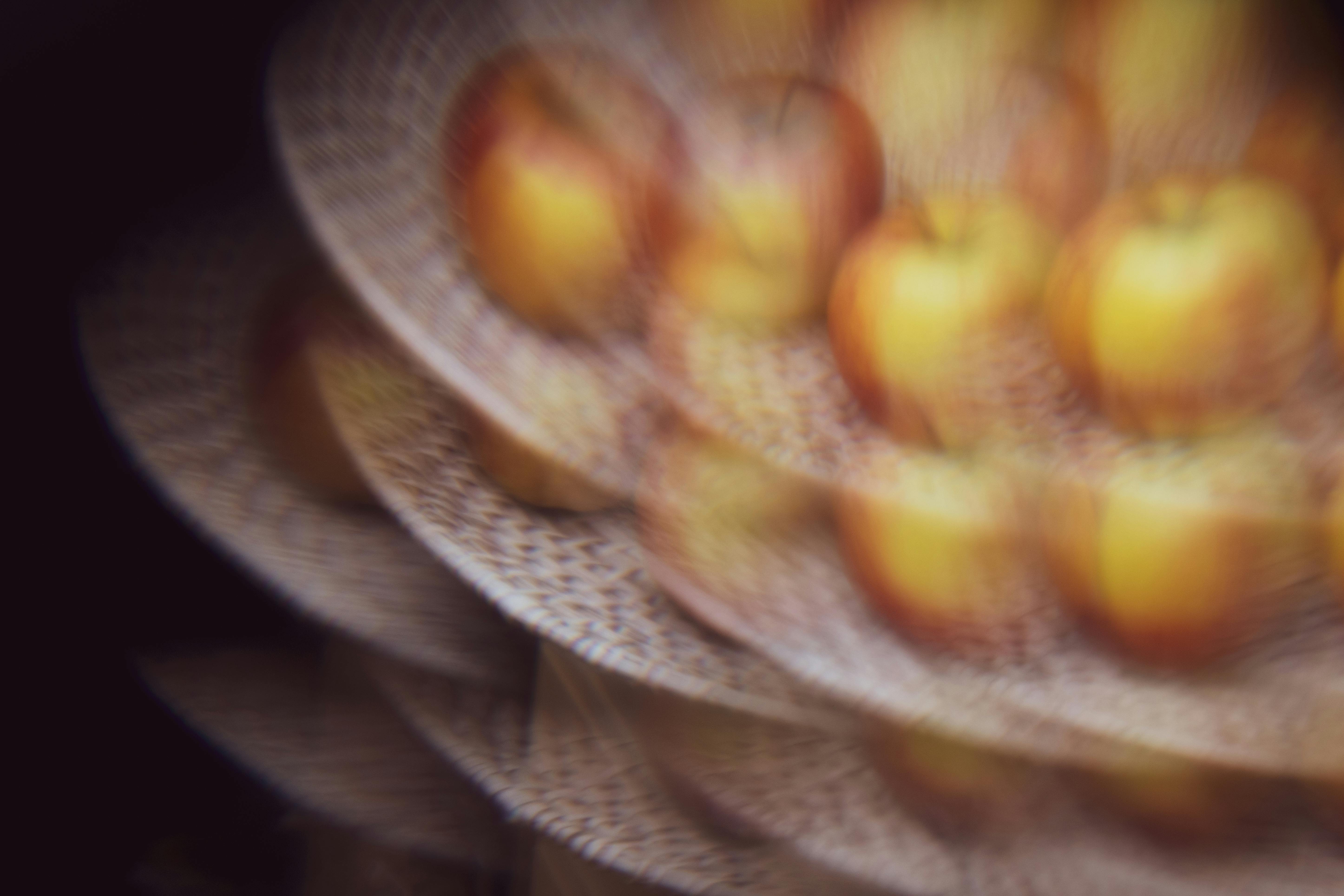 Artistic blurred image of apples on woven plates, creating a distorted effect.