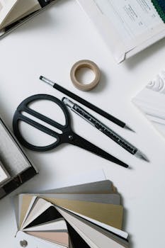 Flat lay of art supplies with scissors, swatches, and stationary for creative work.