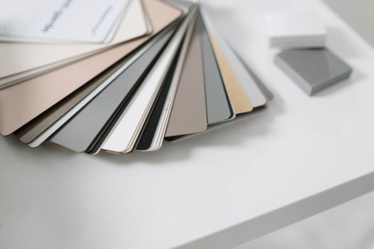 A variety of neutral color samples on a minimalist white desk for design purposes.. variety, neutral, color