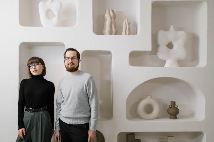 Man And Woman Wearing Long Sleeves Standing In Front Of A Feature Wall