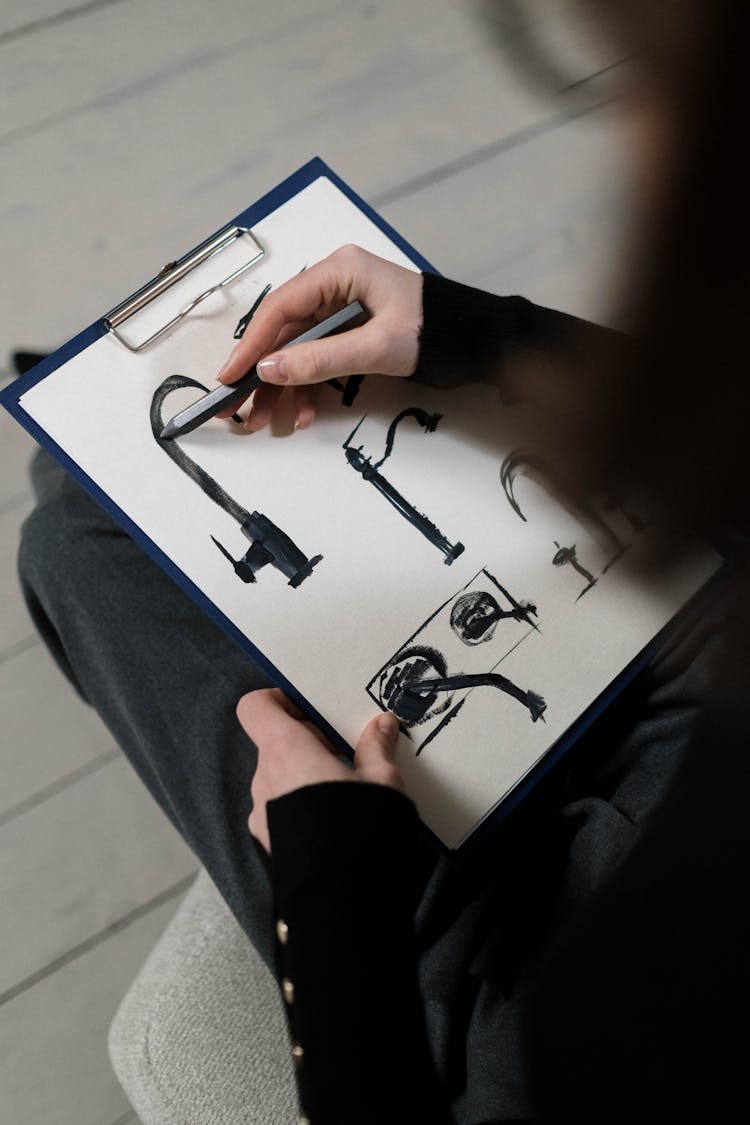 Person Sketching With A Pen On A White Paper On Clipboard