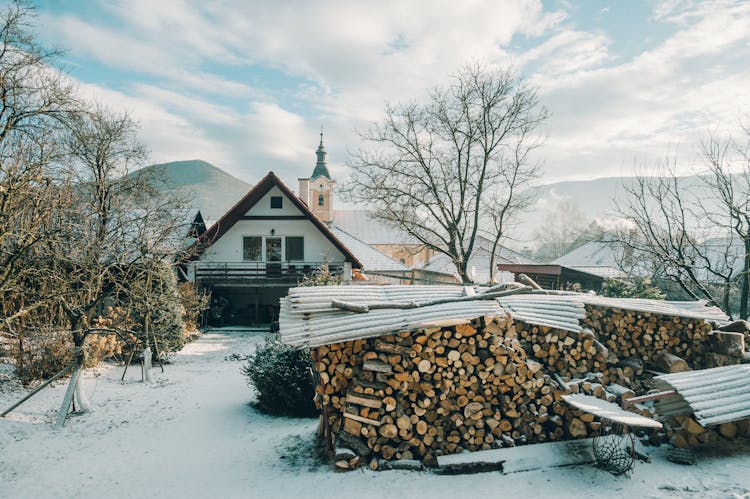 A Pile Of Chopped Fire Wood On The Backyard Of A House 