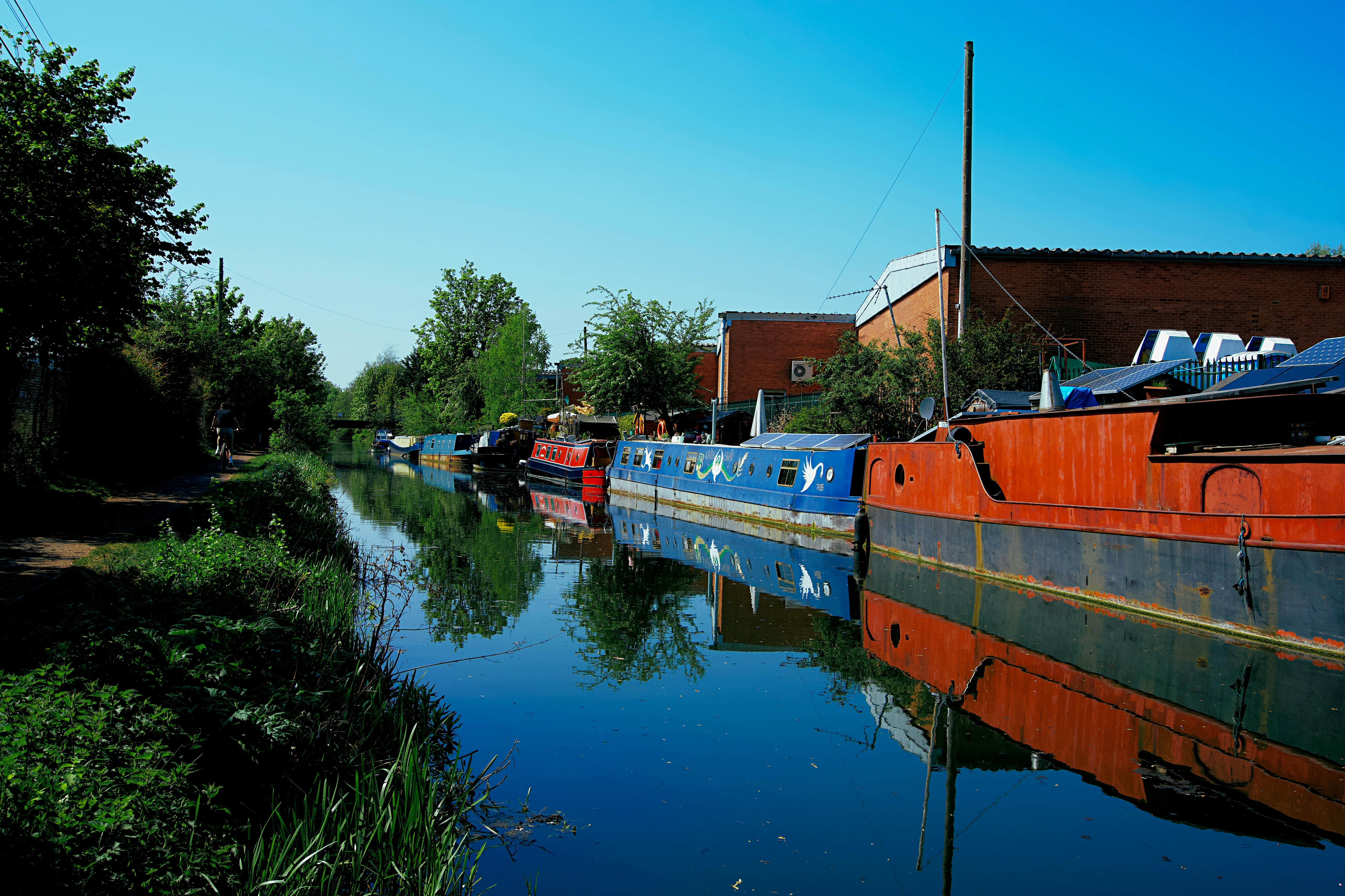 Free Colorful canal boats reflecting on tranquil water in a serene setting in England. Stock Photo