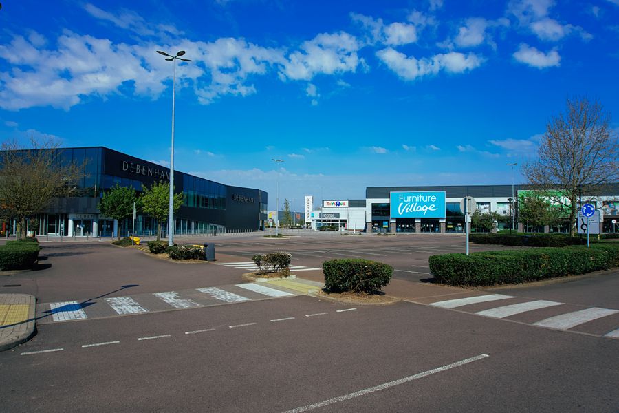Open-air shopping center buildings beyond a parking area