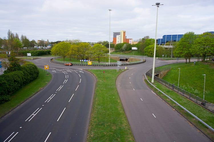 An Orange Car In A Roundabout Of Highways