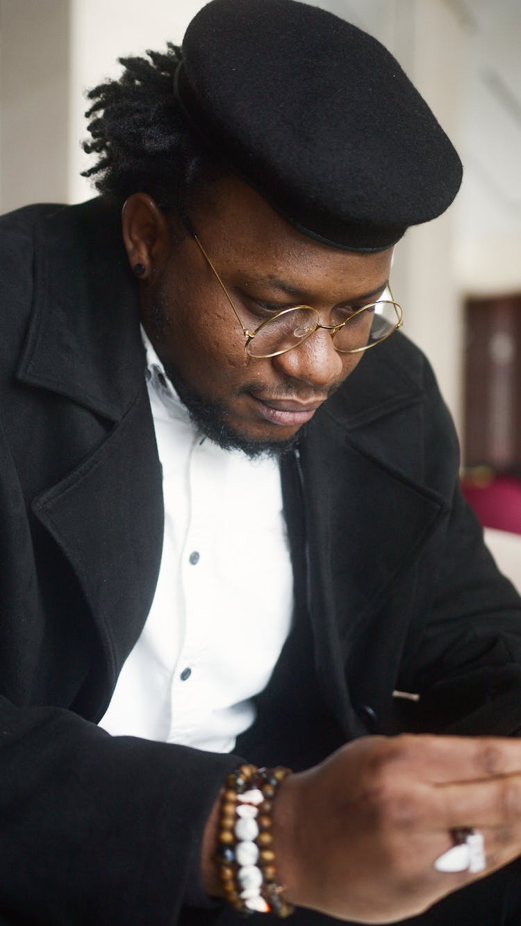 Man Wearing Hat, Eyeglasses And Black Coat Looking Down