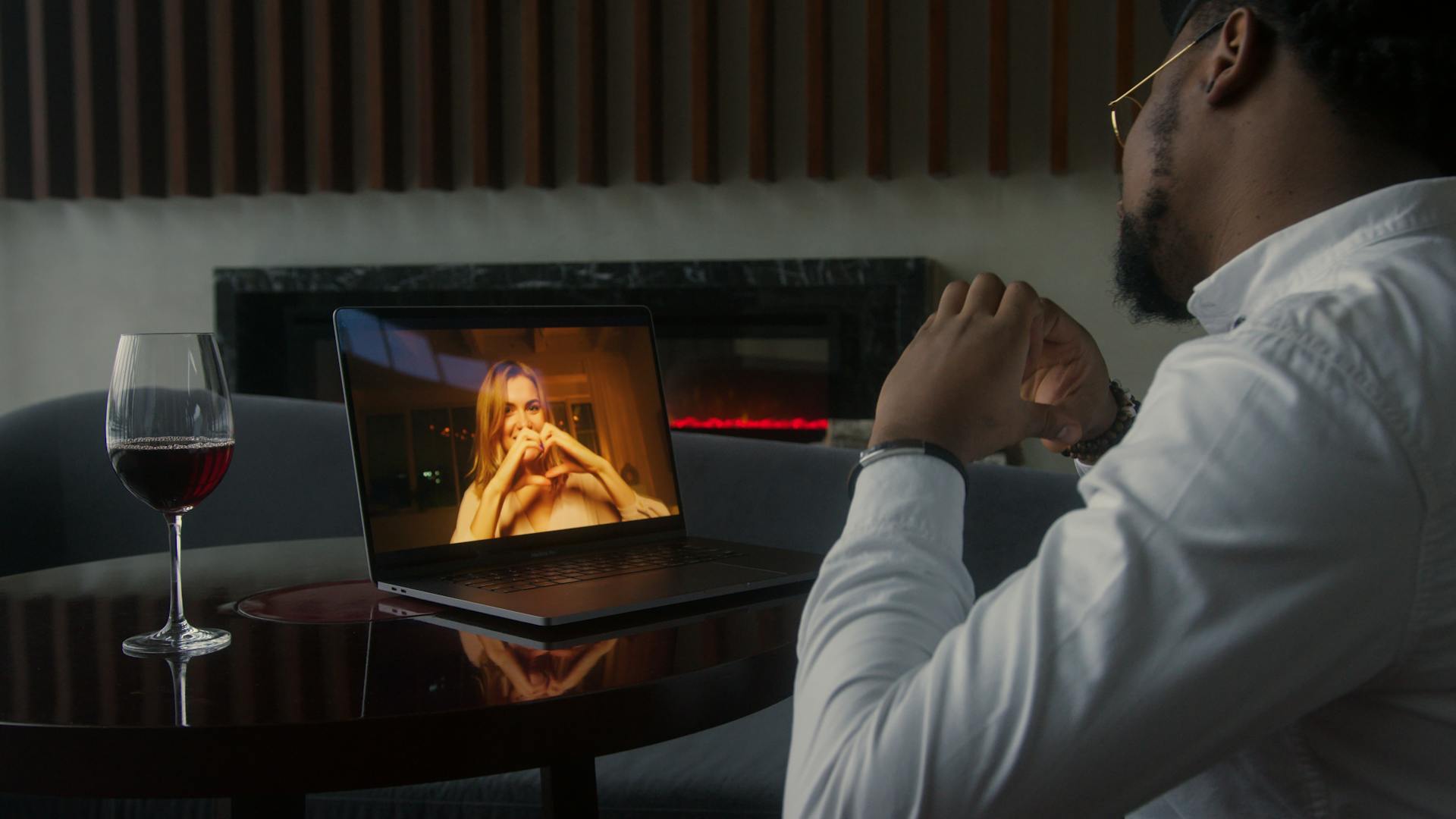 Man having a video call date with wine, enjoying a cozy and intimate atmosphere.