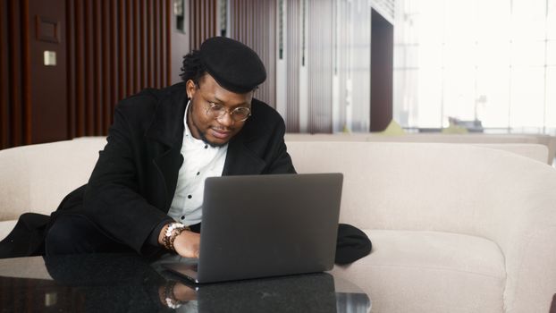 African American man focused on his work using a laptop in a stylish office setting.