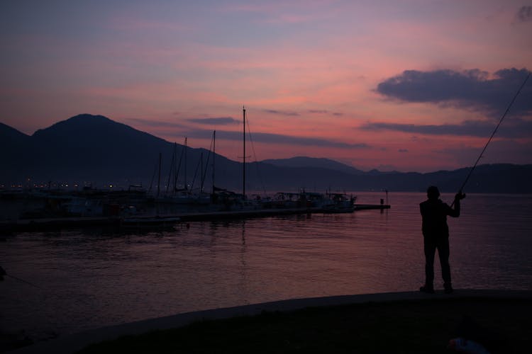 Silhouette Of Man Fishing In Evening