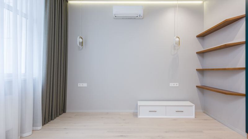 Close up of a sleek white ductless mini split indoor unit mounted high on a living room wall