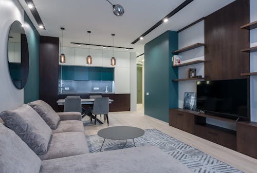 Interior of modern studio apartment with kitchen zone and living room with comfy sofa and TV set placed on wooden cabinet