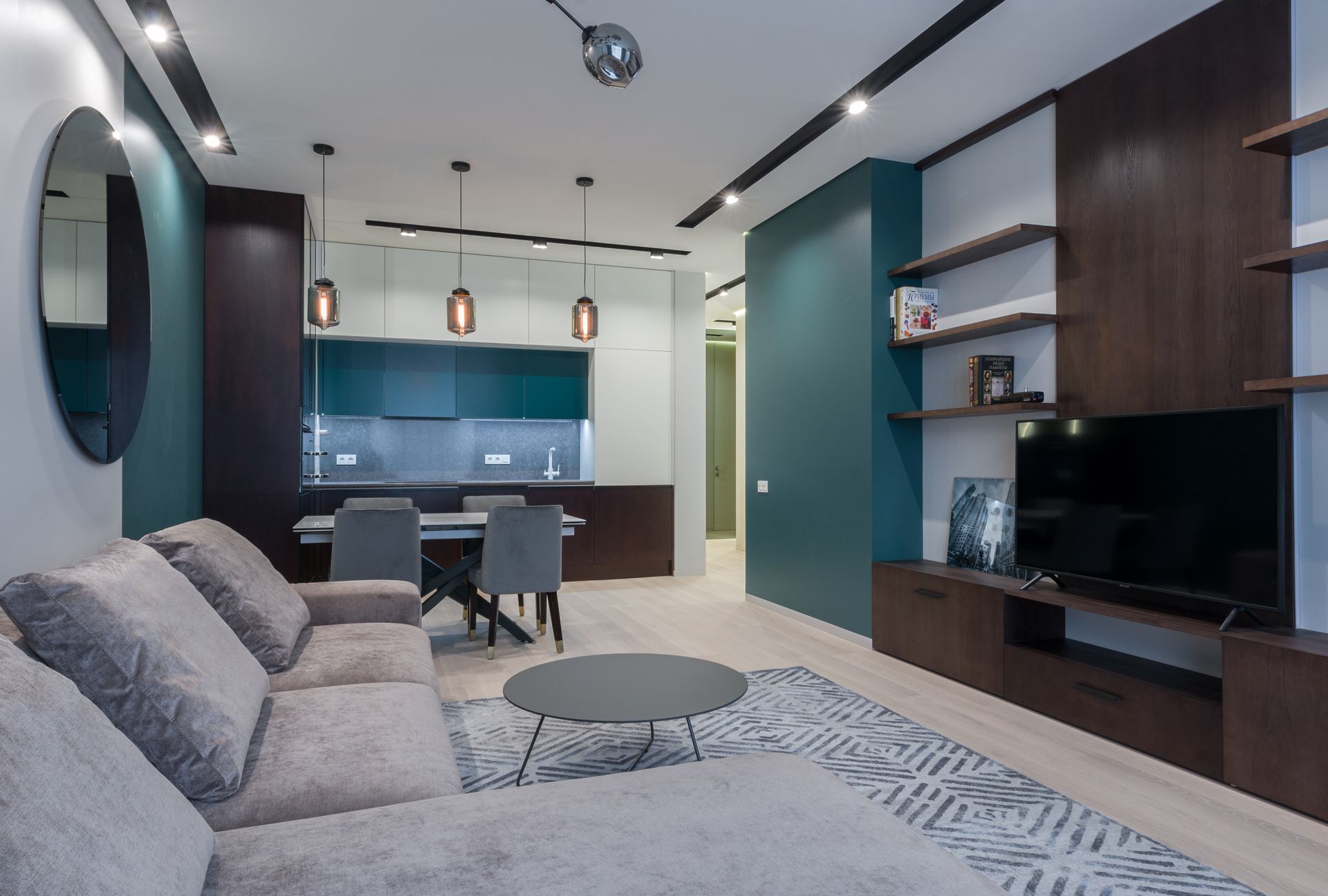 Interior of modern studio apartment with kitchen zone and living room with comfy sofa and TV set placed on wooden cabinet