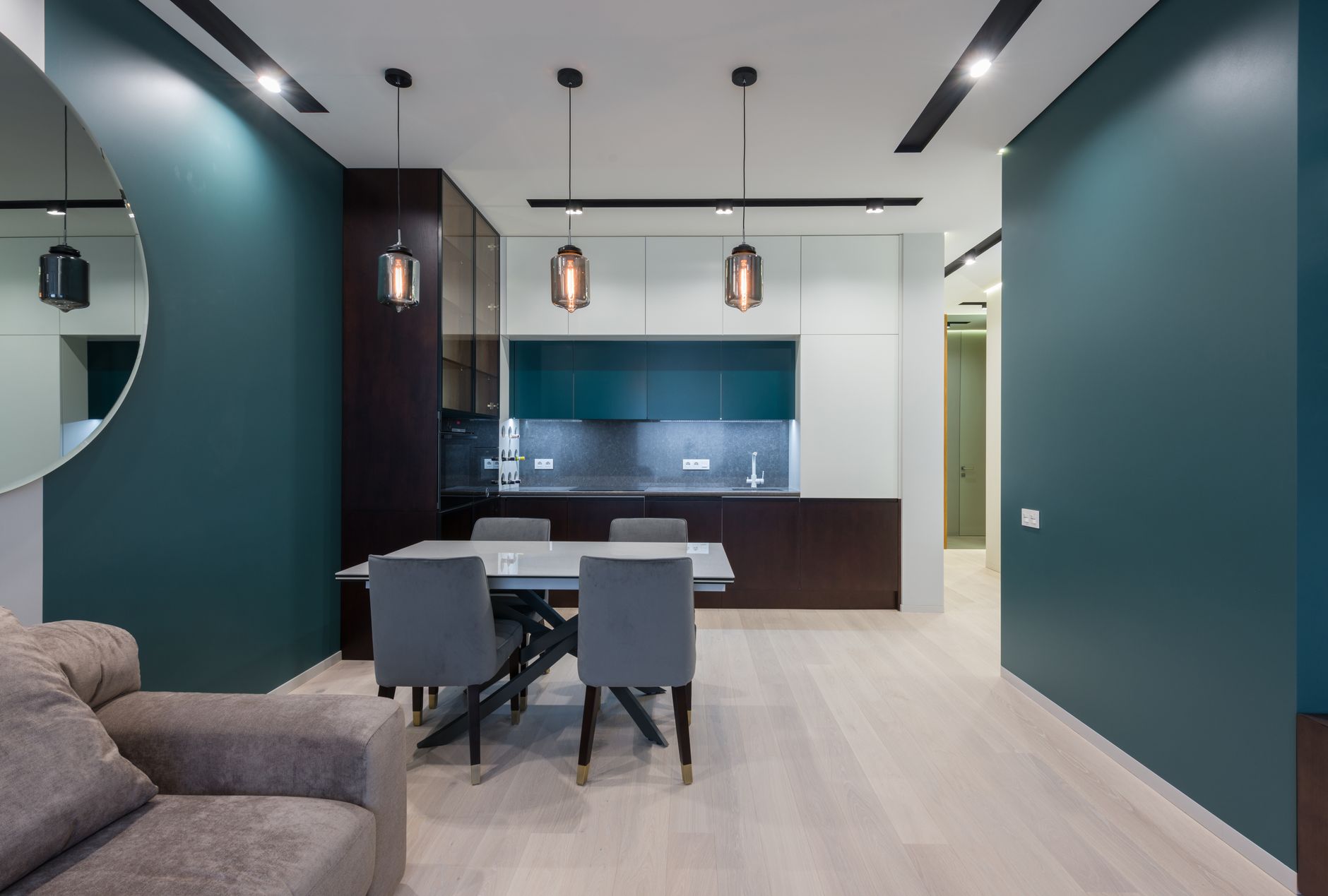 Dining table with chairs in kitchen near comfy sofa in modern studio apartment with creative design