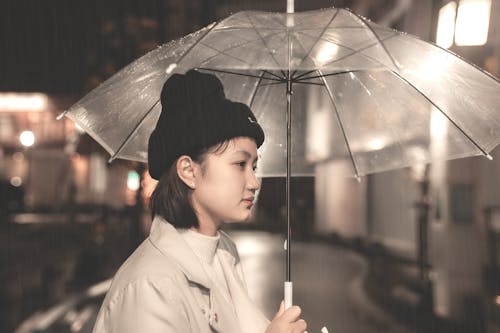 Woman in White Coat Holding Umbrella