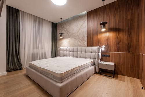 Comfortable soft empty bed placed in stylish modern bedroom in contemporary apartment in minimalistic style