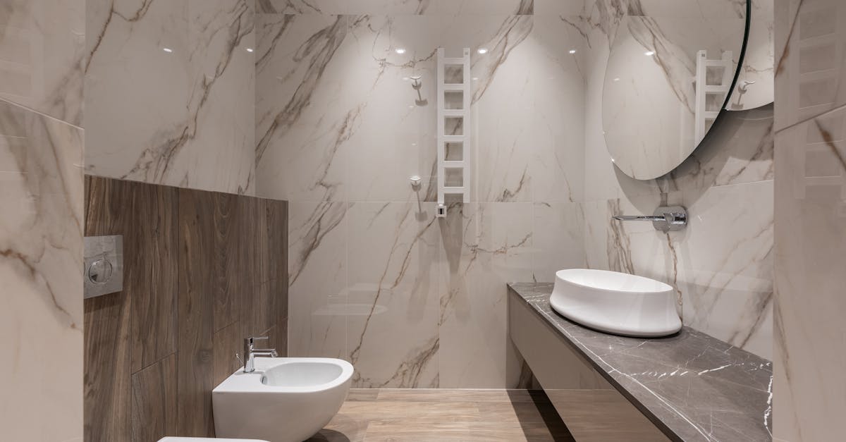 Interior of light modern bathroom with bidet and toilet and sink on cabinet under round mirror on tile