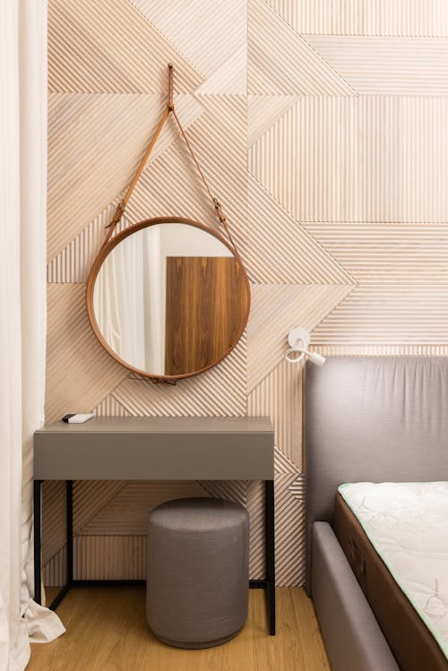 Bedroom interior with mirror and table with pouf near bed
