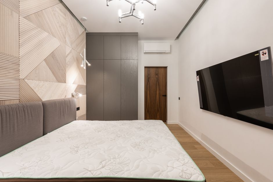 Does Latex Hybrid or Memory Foam Hybrid Last Longer? Myth vs Reality Interior of modern light hotel room with TV on wall near bed and cabinet near door