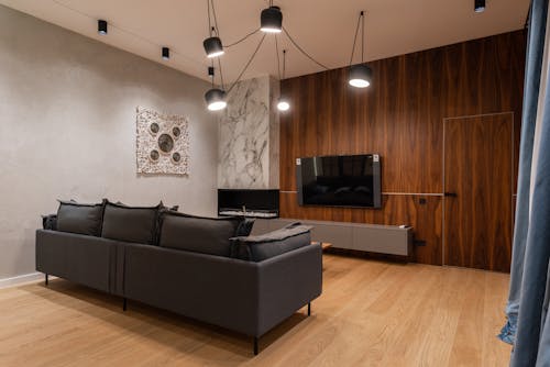 Modern TV hanging on wooden wall in front of comfortable couch in spacious stylish living room