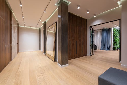 Interior of spacious hallway of modern apartment with wooden walls and floor and big doorway