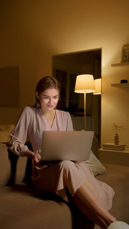 Woman in Pink Dress Using Her Laptop