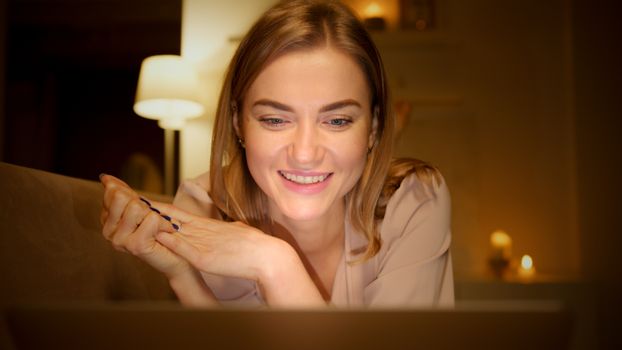 A smiling woman enjoying a relaxed evening indoors in warm lighting.