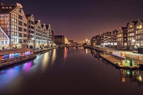 Free Water channel between multistage building exteriors and shiny lights at dusk in Amsterdam Netherlands Stock Photo