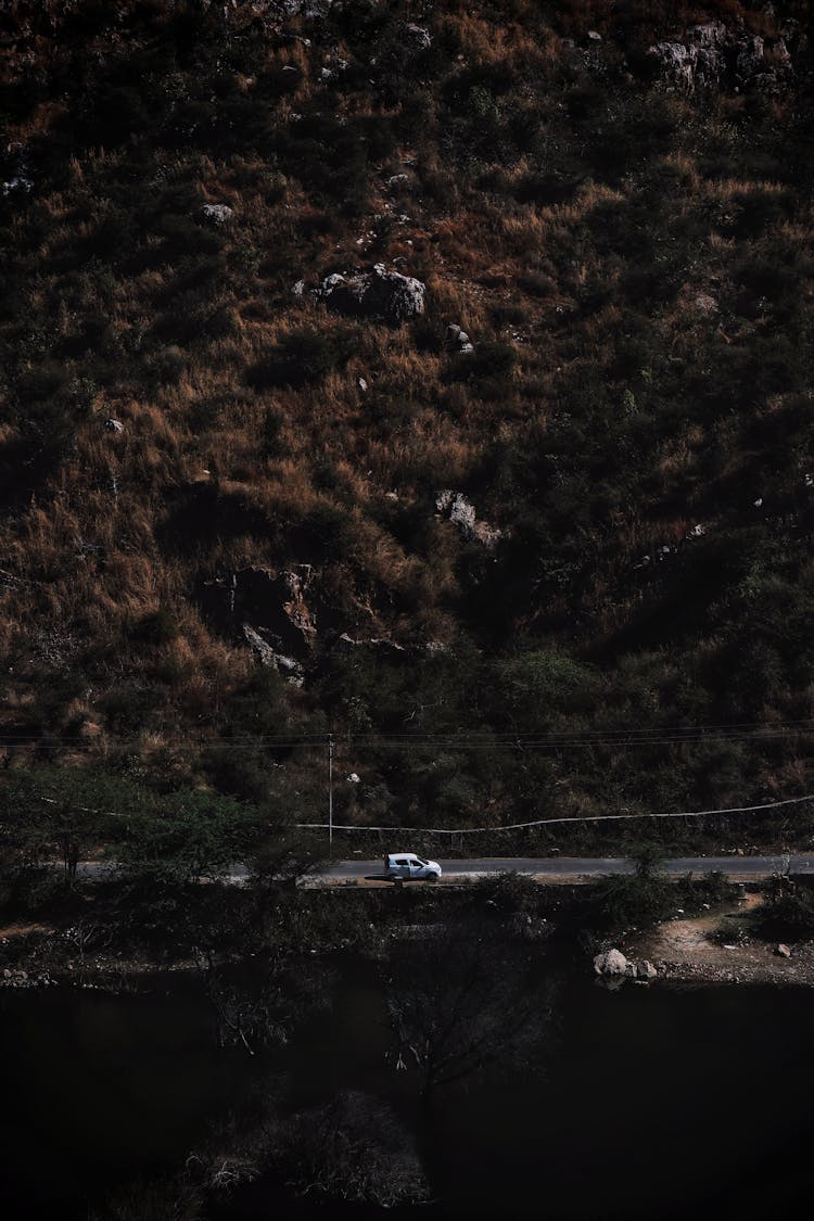 Vehicle On A Road Along A Mountain With Trees