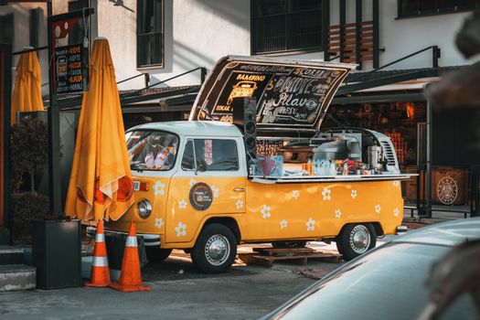 Retro-themed yellow food truck on a city street, serving refreshments with a vintage vibe.