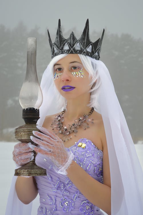 Woman wearing dress and crown with kerosene lamp on snow