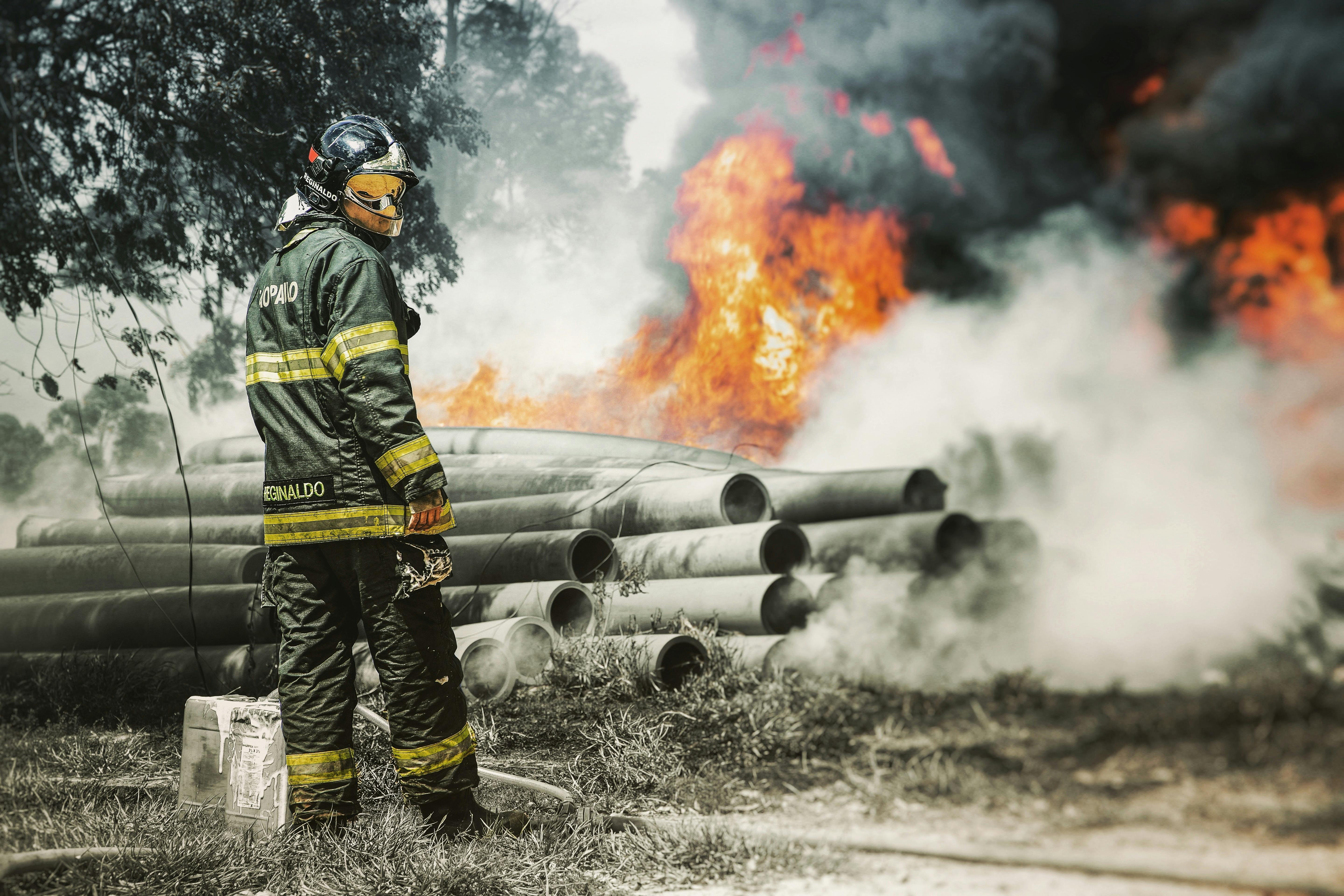 a fireman in uniform standing near the blazing fire