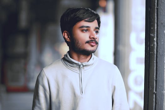 A young man with a beard gazes thoughtfully in Lahore, Pakistan. Soft lighting and blurred background add depth.