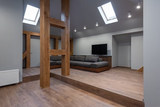 Comfortable corner sofa with cushions placed in spacious living room with wooden details and parquet floor in house