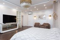 Interior of spacious classic styled bedroom decorated with golden chandelier and lamps