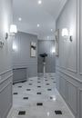 Elegant shining lamps and paintings hanging on gray walls in hallway of classic styled house with marble floor