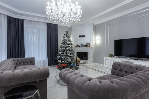 Spacious living room with comfy couch and armchair decorated with Christmas tree