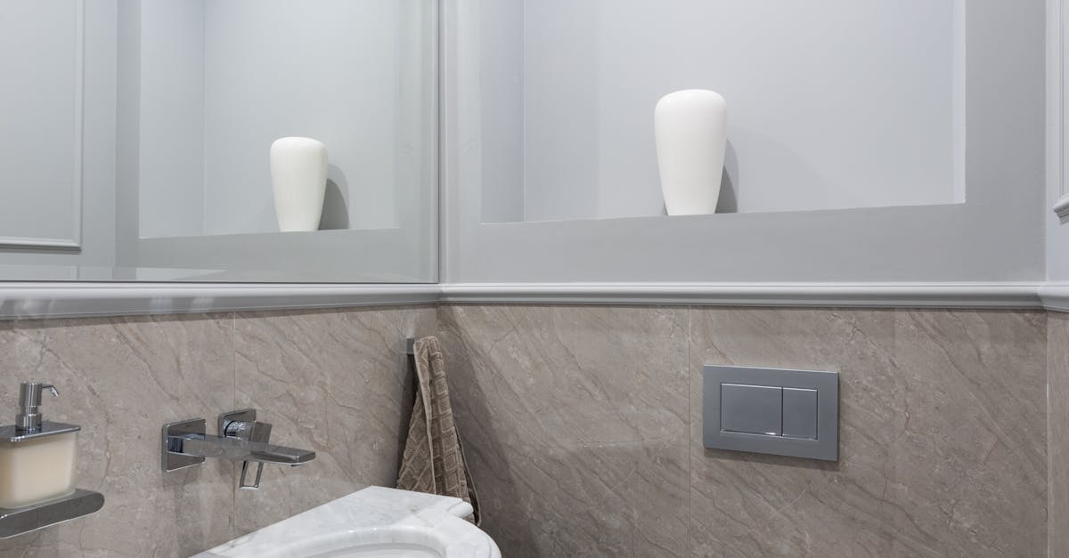 Marble sink and ceramic toilet in modern bathroom with mirror and tiled walls