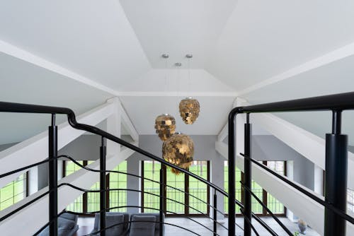 Interior of modern living room with shimmering golden pendant lamps in living room with metal stairs