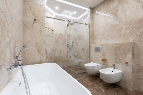 Interior of marble bathroom with glass shower cabin glowing with bright luminous lights