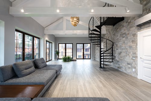 Contemporary living room with curvy black stairs and large windows in bright daylight