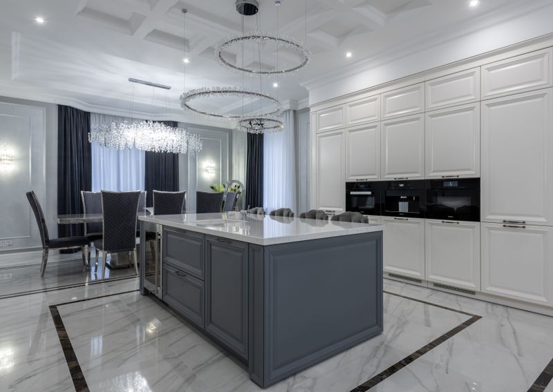 Kitchen with marble counter and wooden dining table on glossy floor tiles