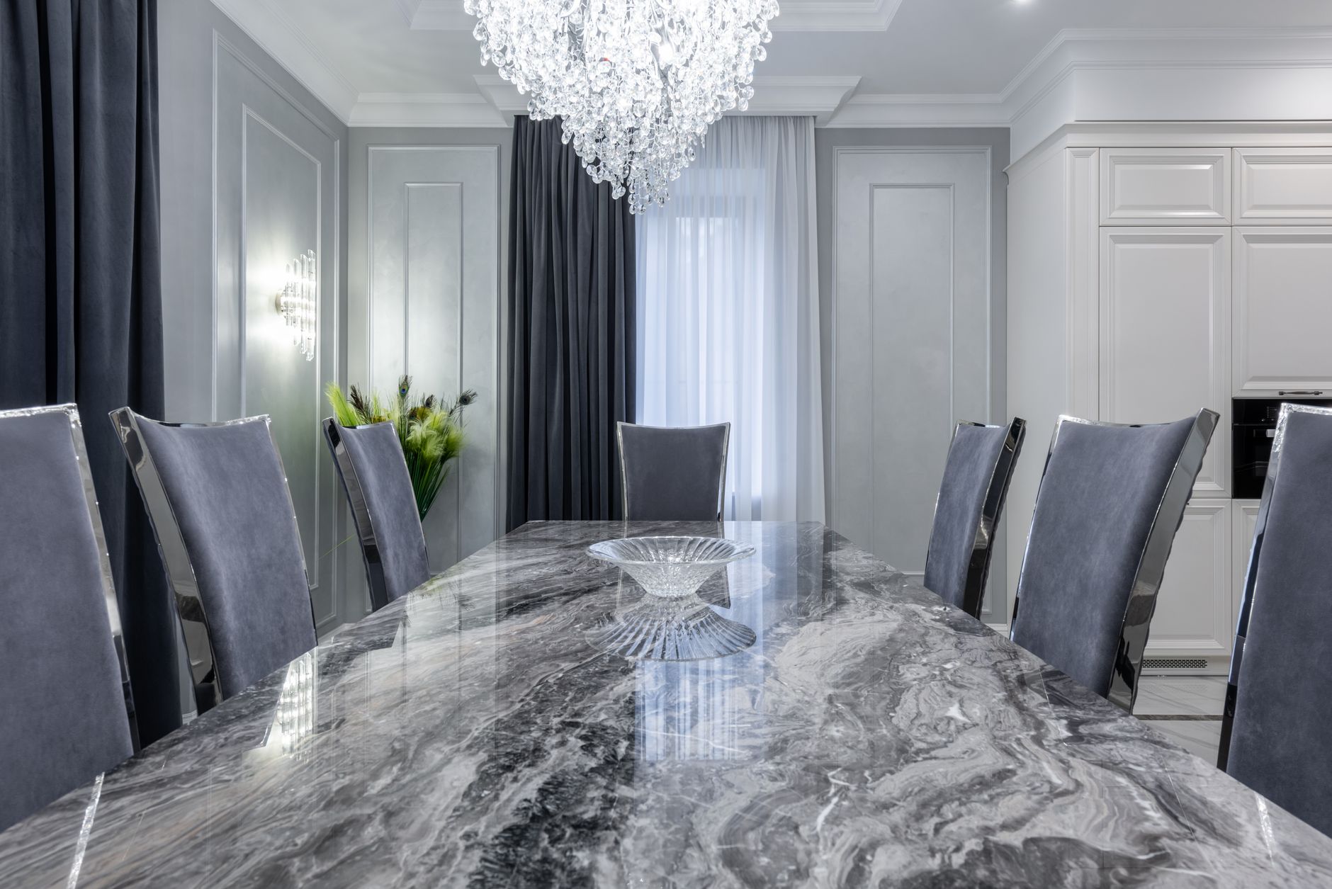 Interior of contemporary dining room with stylish marble table and comfortable chairs in light apartment in daytime