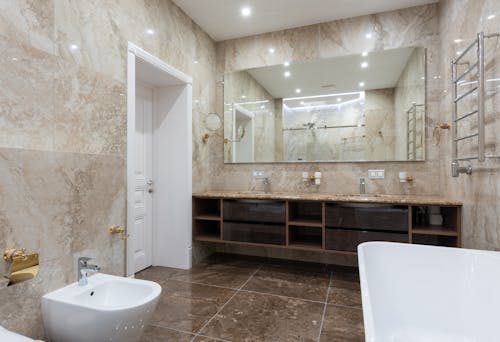 Bathroom with bidet and bathtub near sink on counter