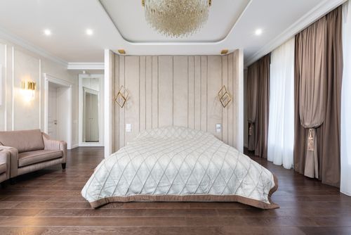 Free Interior of modern bedroom with bed next to armchairs under chandelier with curtains on windows Stock Photo