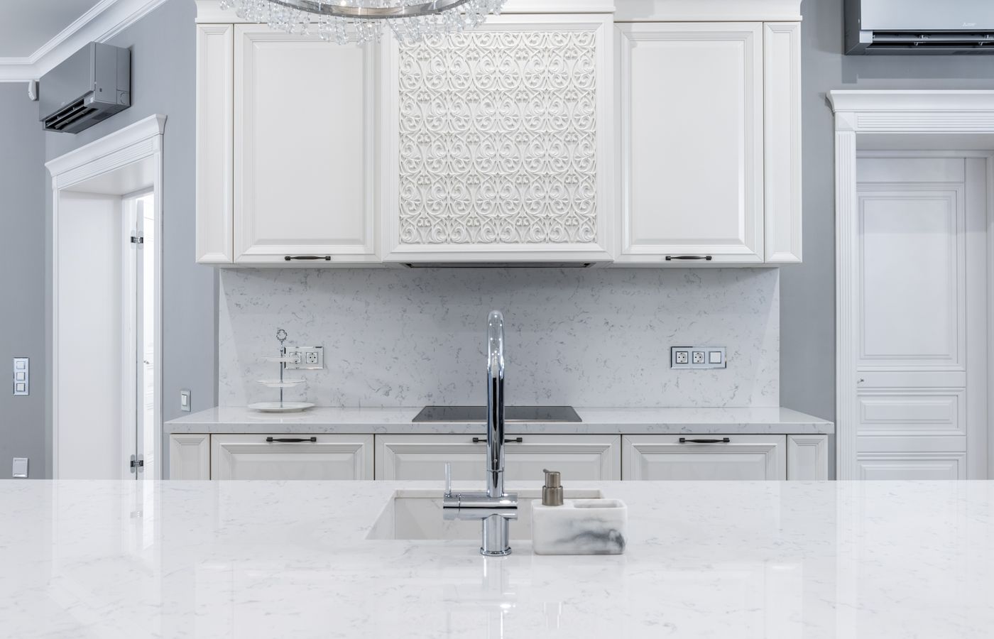 Classic white kitchen with paneled cabinet doors, pale veined worktops and restrained traditional detailing