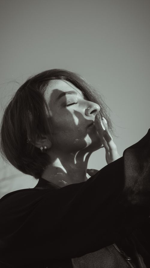 Free A captivating portrait of a woman with eyes closed, embracing shadows and light in a serene outdoor setting. Stock Photo