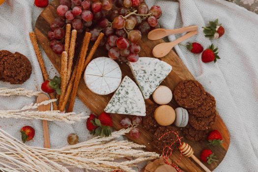 An overhead view of a rustic cheese board featuring grapes, cheese, and assorted snacks.