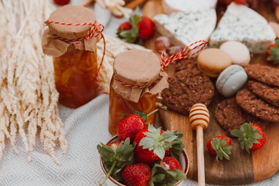 Delightful spread of homemade jam, strawberries, cheese, and cookies on a picnic table.