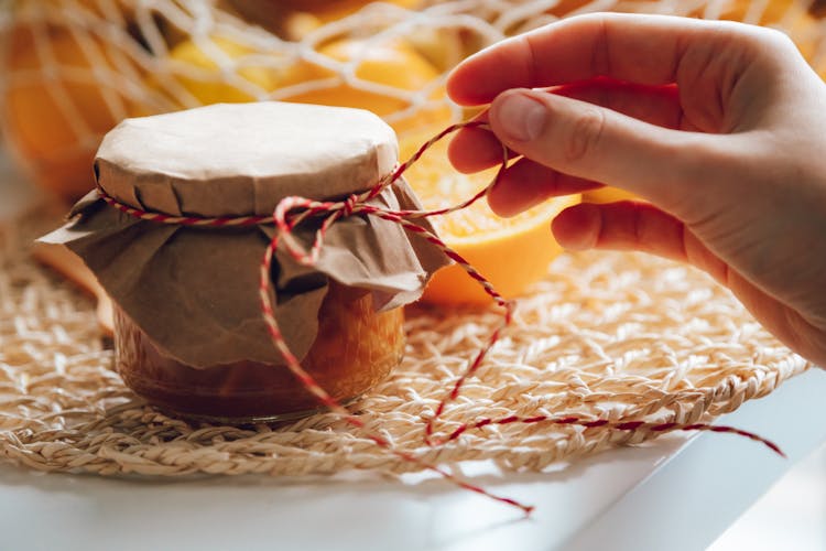 Close-up Of A Woman Touching A Thread Attached To A Jar